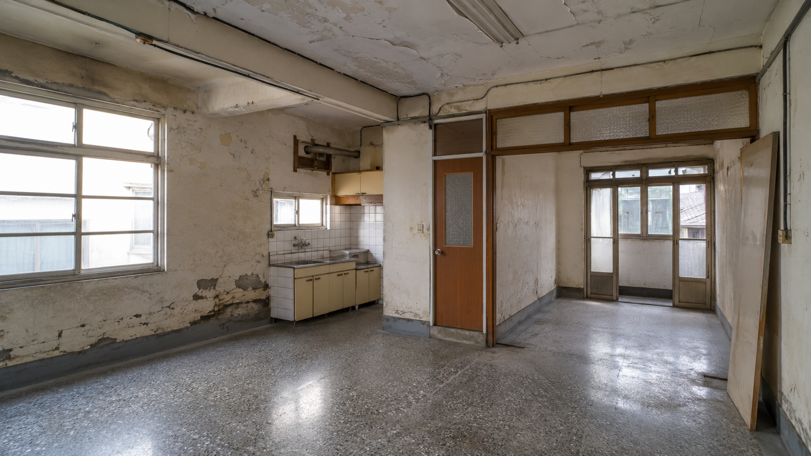 台灣老屋翻新前清空空間照片，可見裂縫、滲水、外露管線與舊地坪，呈現預算有限時應優先處理基礎工程。