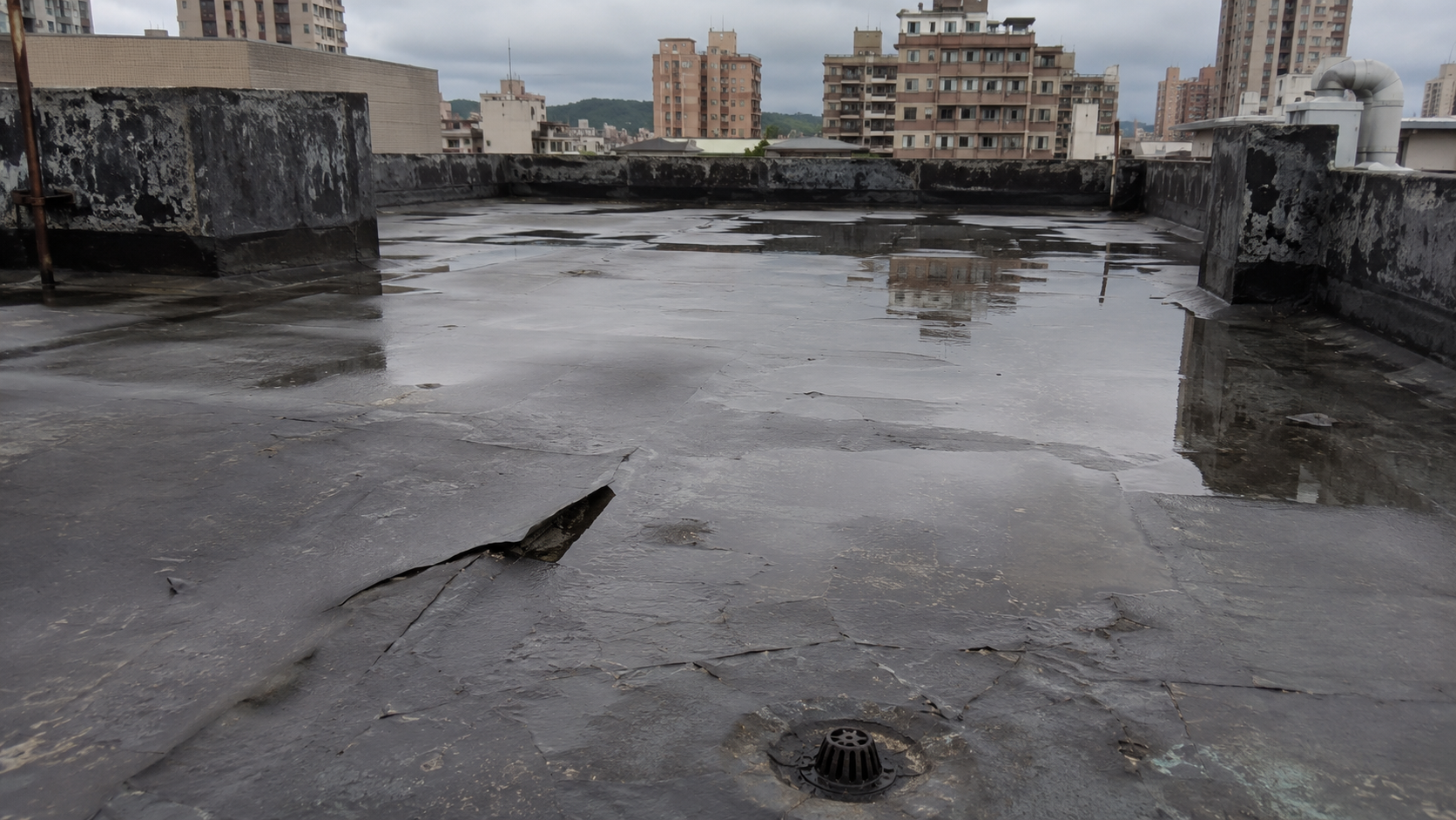 平屋頂防水層老化、局部起泡與積水情況，呈現屋頂現場常見異常。