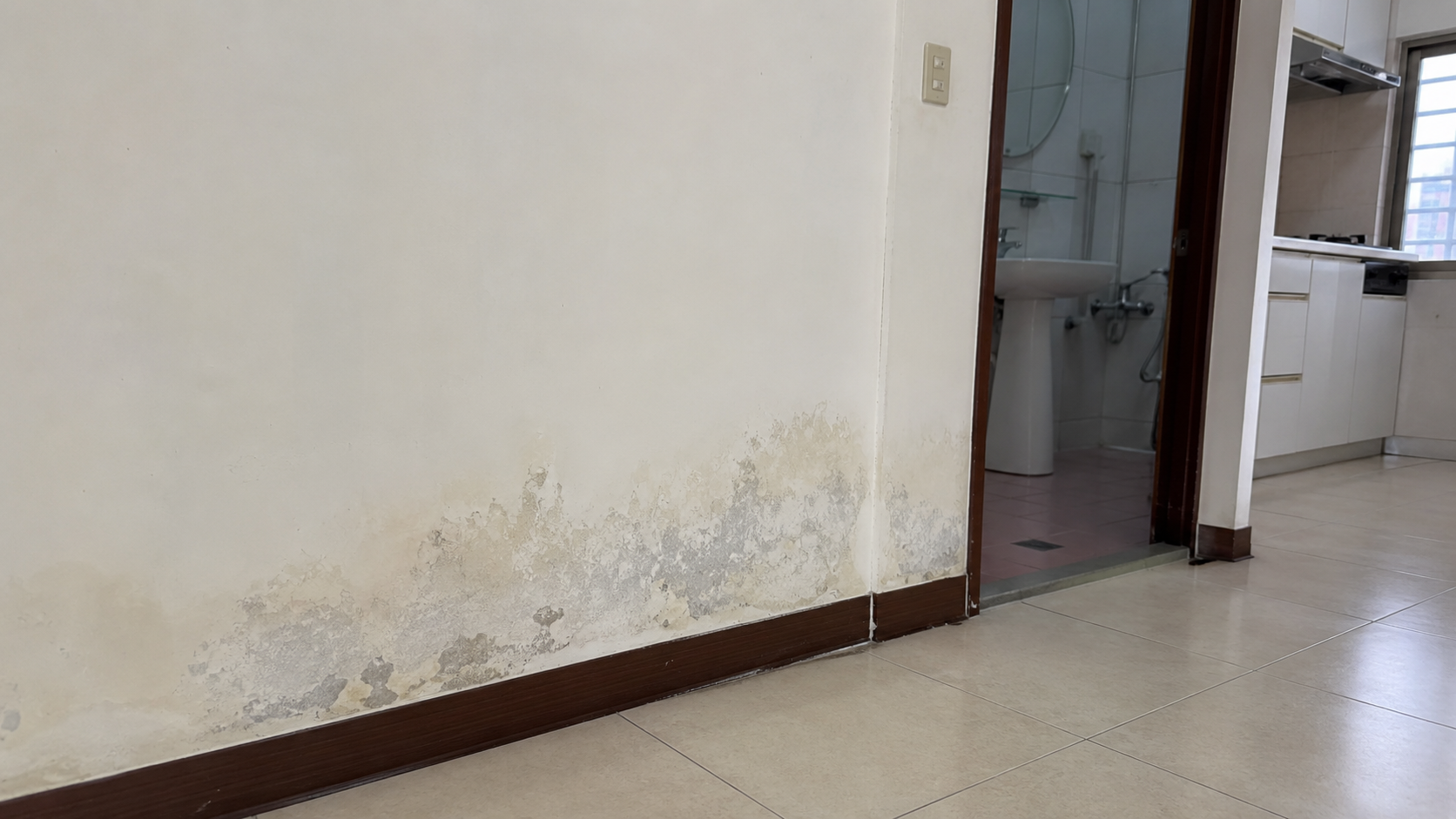 室內牆角與踢腳板附近出現持續潮濕與水痕的住宅照片。